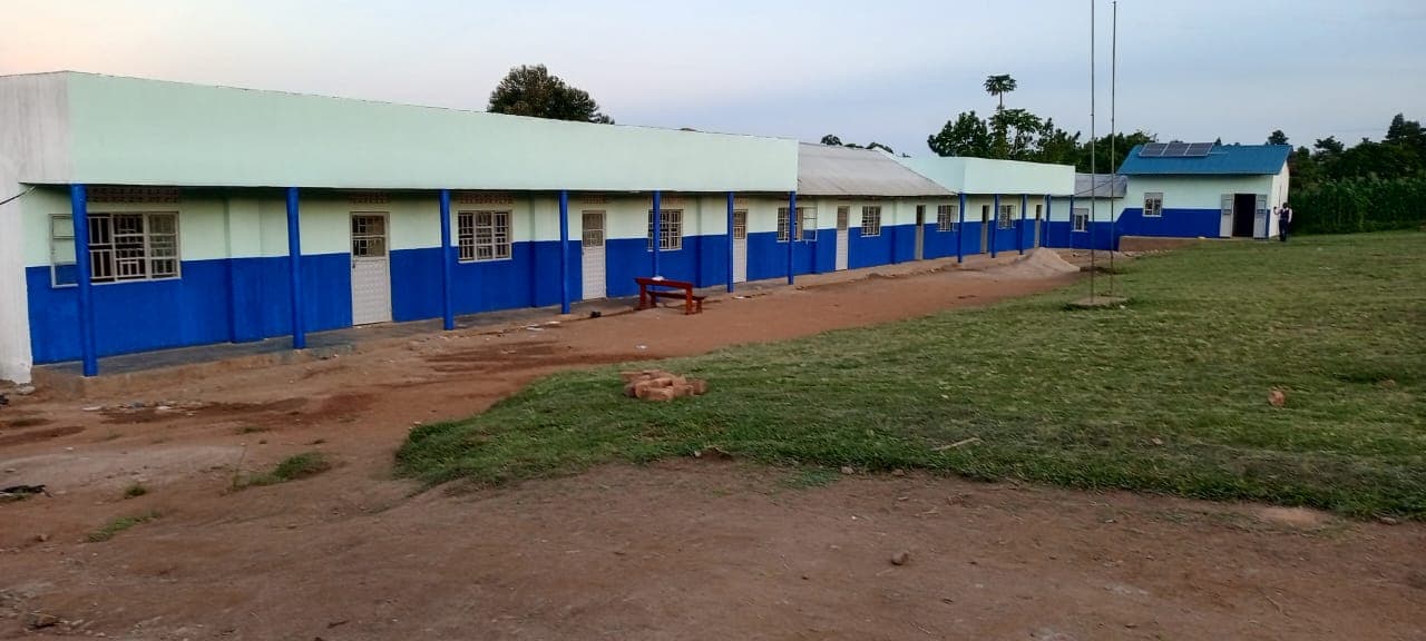 Renovated school building with a fresh white exterior and the Uganda flag.