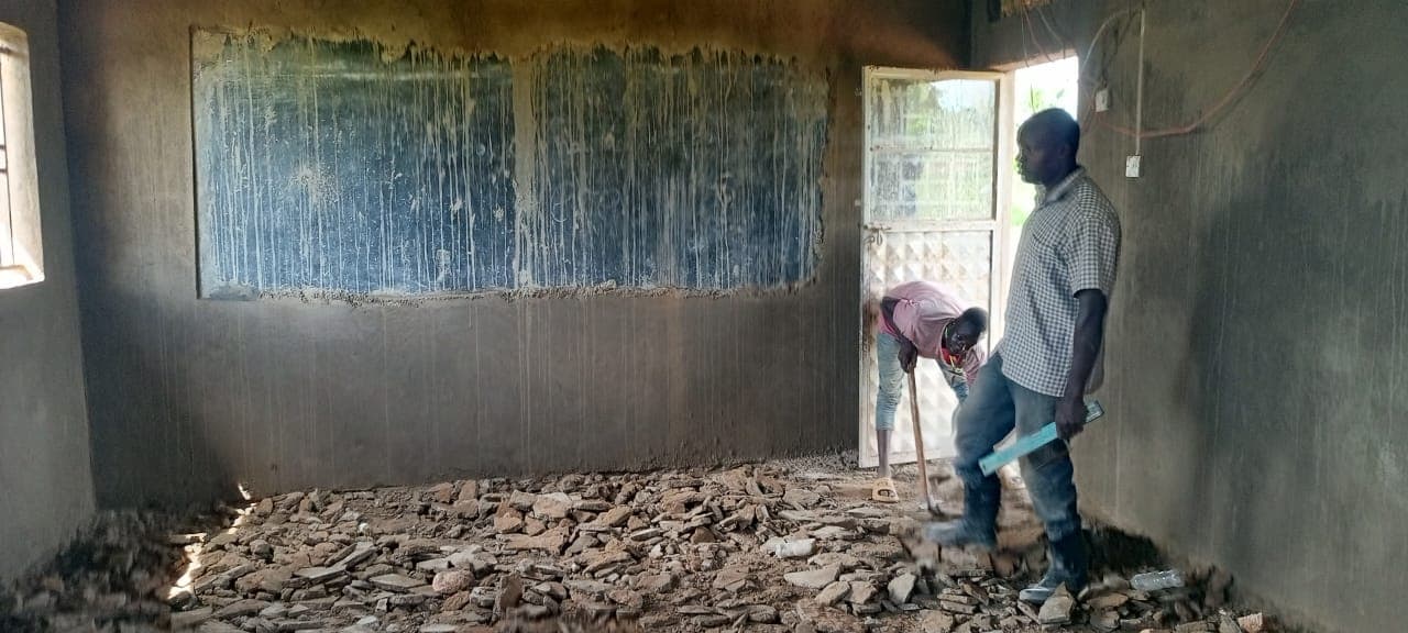 Workers clearing rubble from a classroom floor before renovation