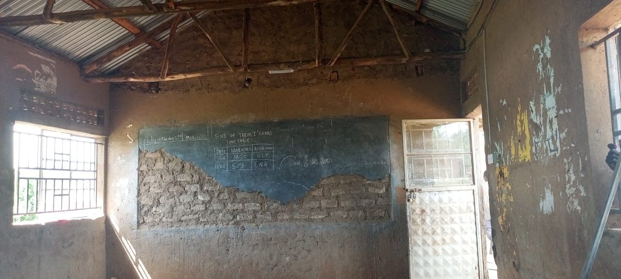 Classroom before renovation with exposed masonry and a damaged floor