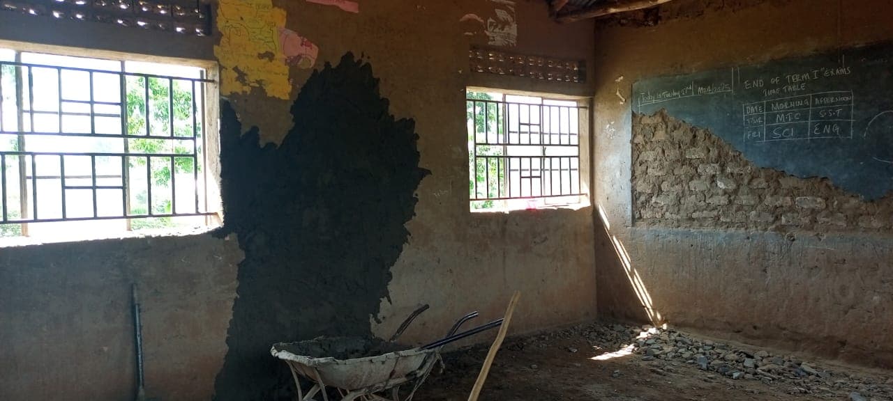 Classroom before renovation with damaged walls and exposed masonry