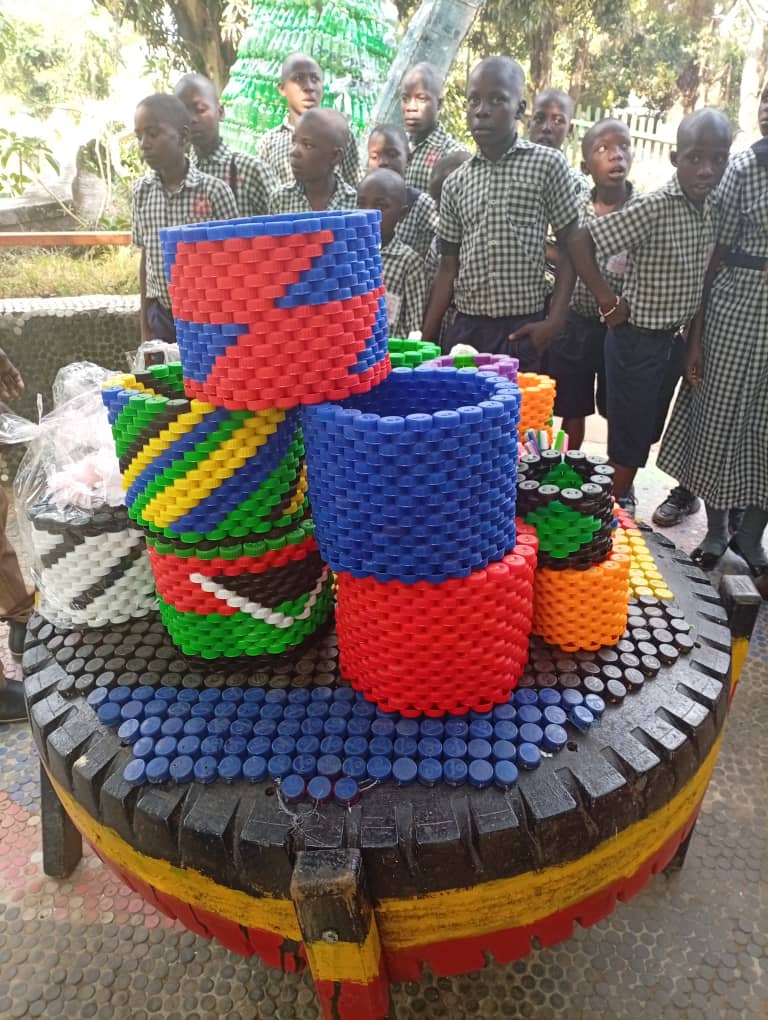 Pupils learning about recycled crafts made from bottle caps