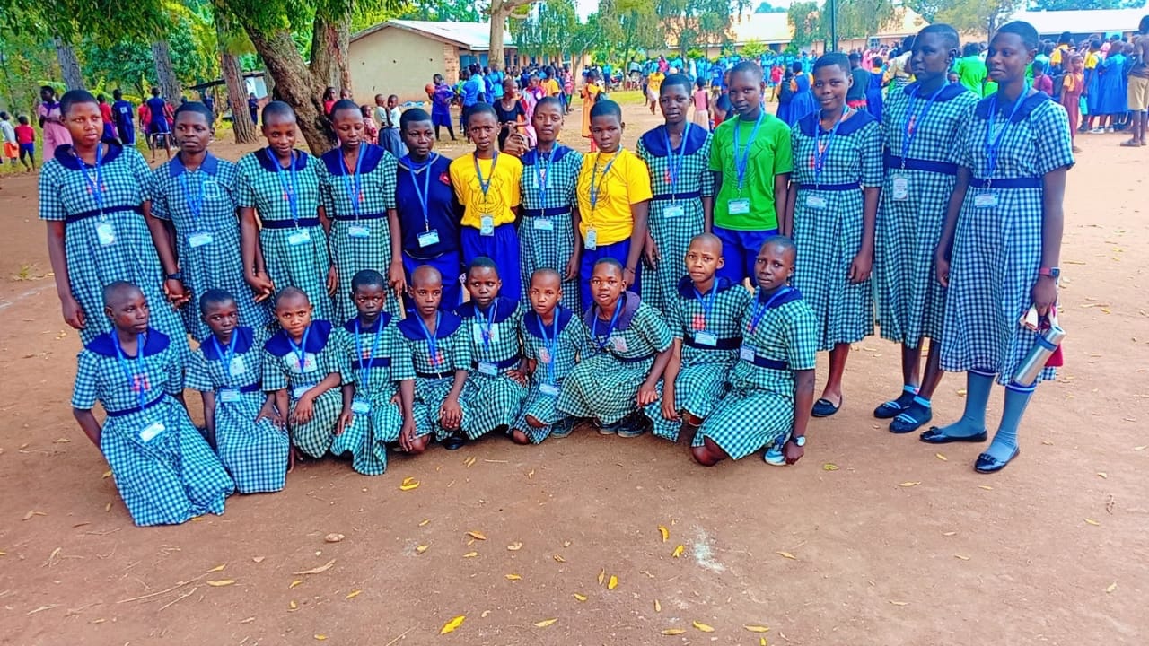 Pupils posing together on the school grounds with the school building behind them